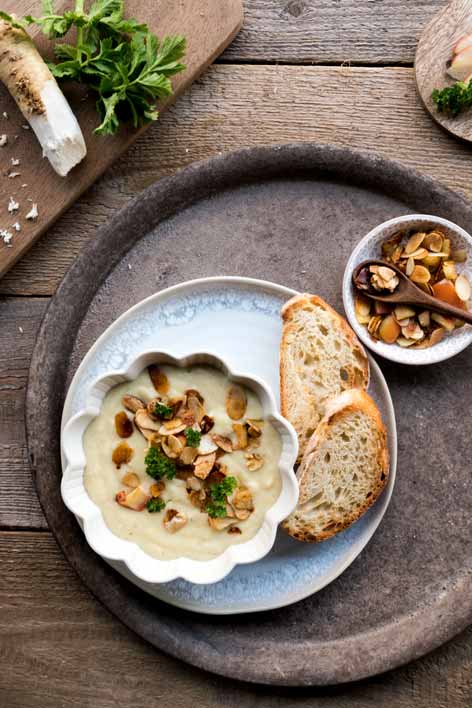 Eine Schüssel mit Meerrettich-Pastinaken-Suppe dekoriert mit Äpfeln und Nüssen sowie geröstetem Weißbrot