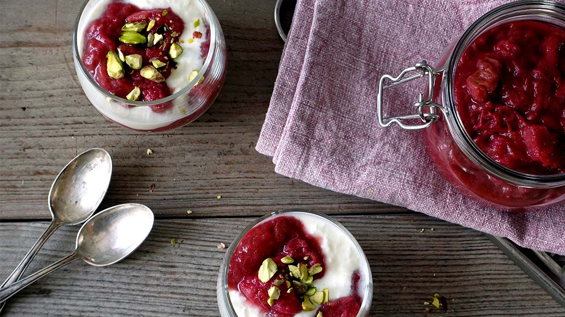 Zwei Gläser selbstgemachter cremiger Naturjoghurt aus Oberpfälzer Rohmilch, verfeinert mit Rhabarberkompott und gehackten Pistazien