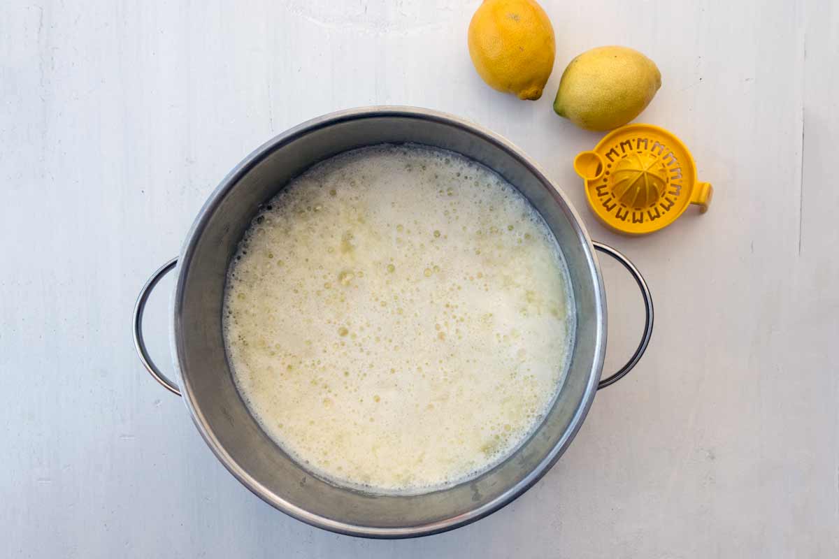 Zwei Töpfe. Einer enthält geronnene Milch. Der andere einen Sieb mit Käsebruch und flüssiger Molke.