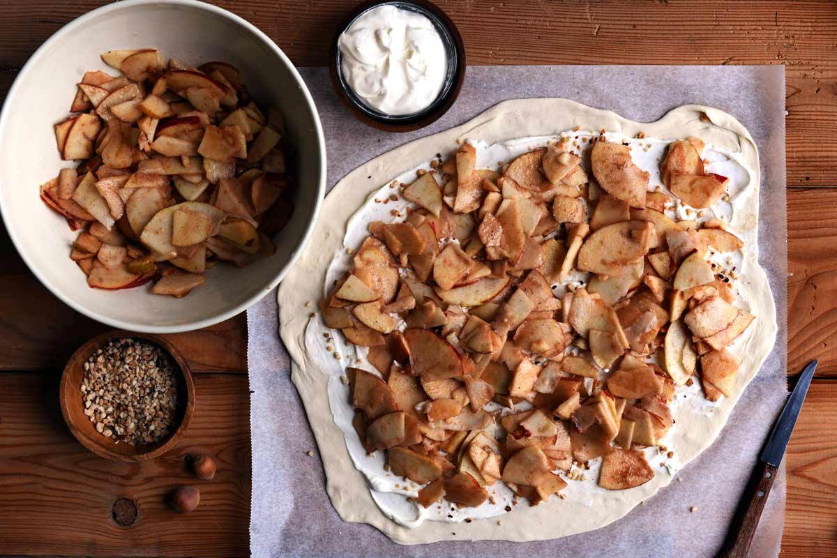 Mit Schmand, Haselnüssen und Äpfeln belegter Strudel