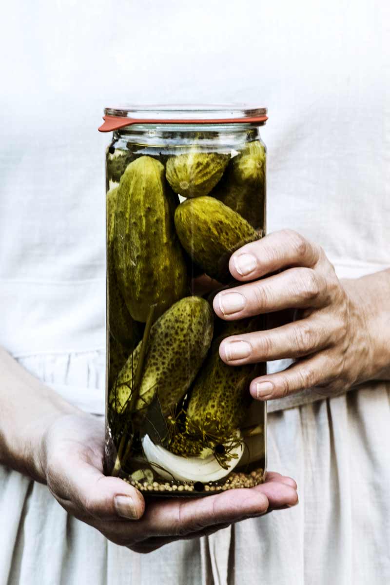 Eine Frau hält ein Glas mit eigelegten Gewürzgurken in den Händen