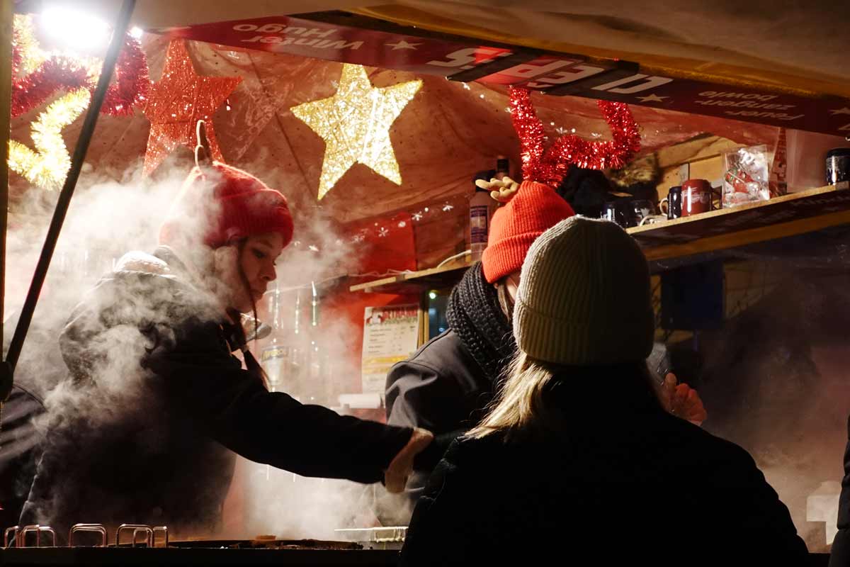 Zwei Frauen mit roten Mützen backen Crêpes auf dem Burglengenfelder Adventsmarkt