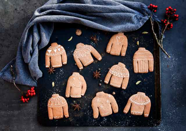 Weihnachtliche Ugly Sweater Kekse auf einem schwarzen Backblech