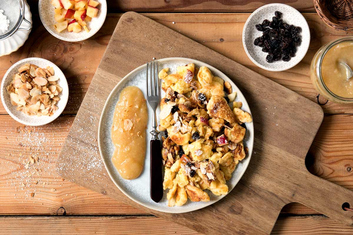 Eine Portion Kaiserschmarrn auf einem Teller angerichtet mit Apfelmus