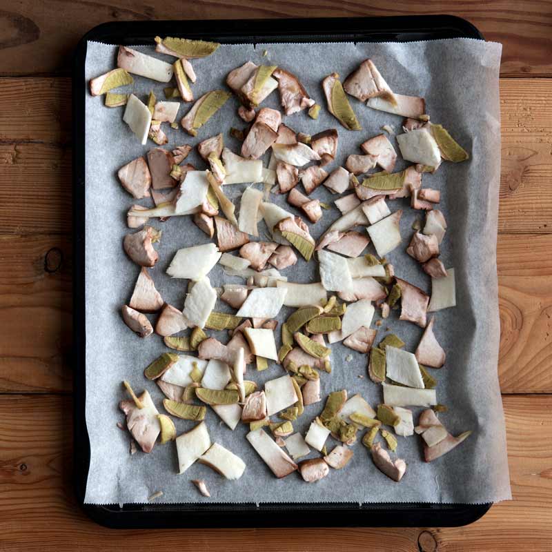 Ein Backblech voll mit in Scheiben geschnittenen Steinpilzen die zum Trocknen ausgelegt sind