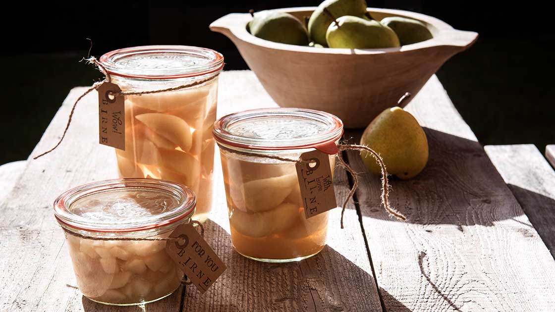Eine Hand hält eine Holzschale mit Birnen
