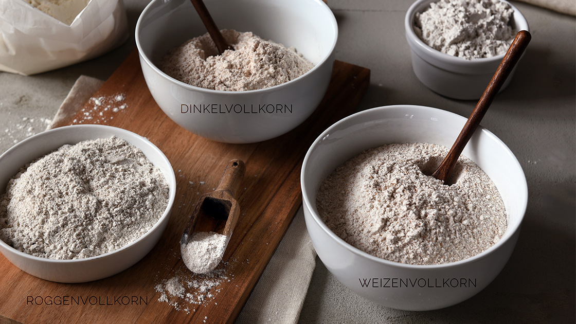 Unterschiedliche Vollkornmehlsorten für Sauerteig in Schüsseln