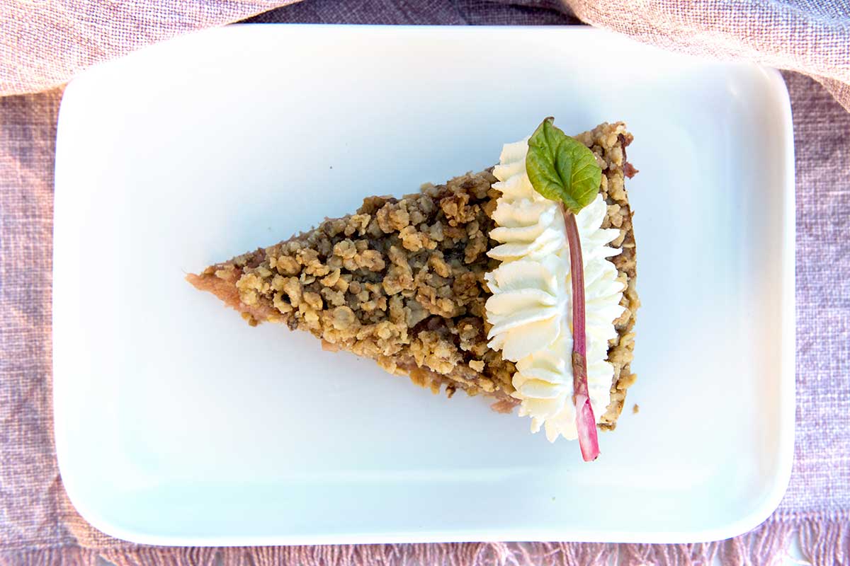 Rhabarber-Streuselkuchen mit Sahnehaube auf weißem Teller