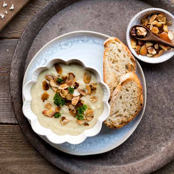 Eine Schüssel mit Meerrettich-Pastinaken Suppe dekoriert mit Äpfeln und Mandeln